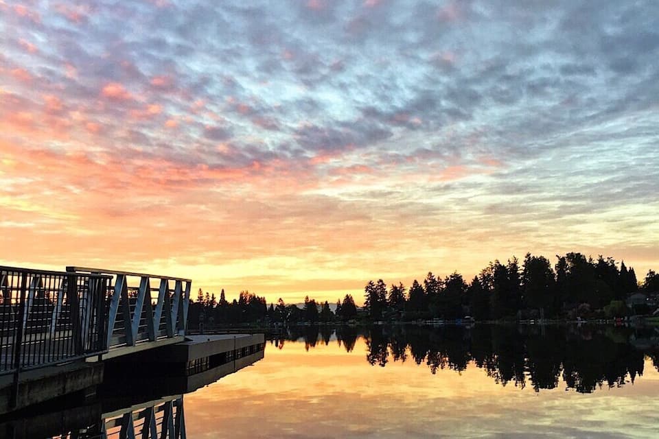 Un capvespre sobre un llac tranquil amb un pont que reflecteix el cel.
