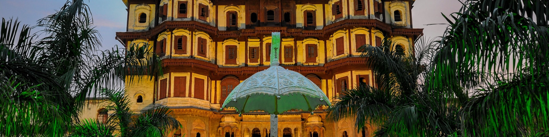 A historic building with ornate architecture, a statue, and palm trees.