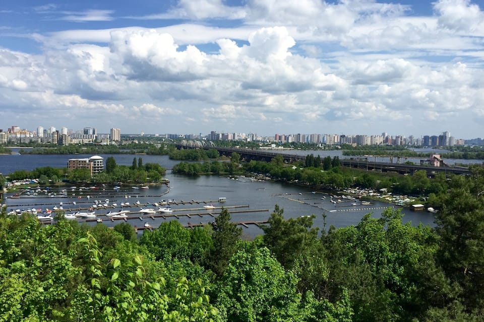 A river with boats, a bridge, and a city skyline in the background.