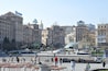A bustling square with historic buildings, a prominent golden dome, and a McDonald's sign.