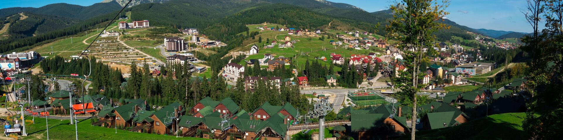 A mountainous town with ski lifts, houses, and a winding road.