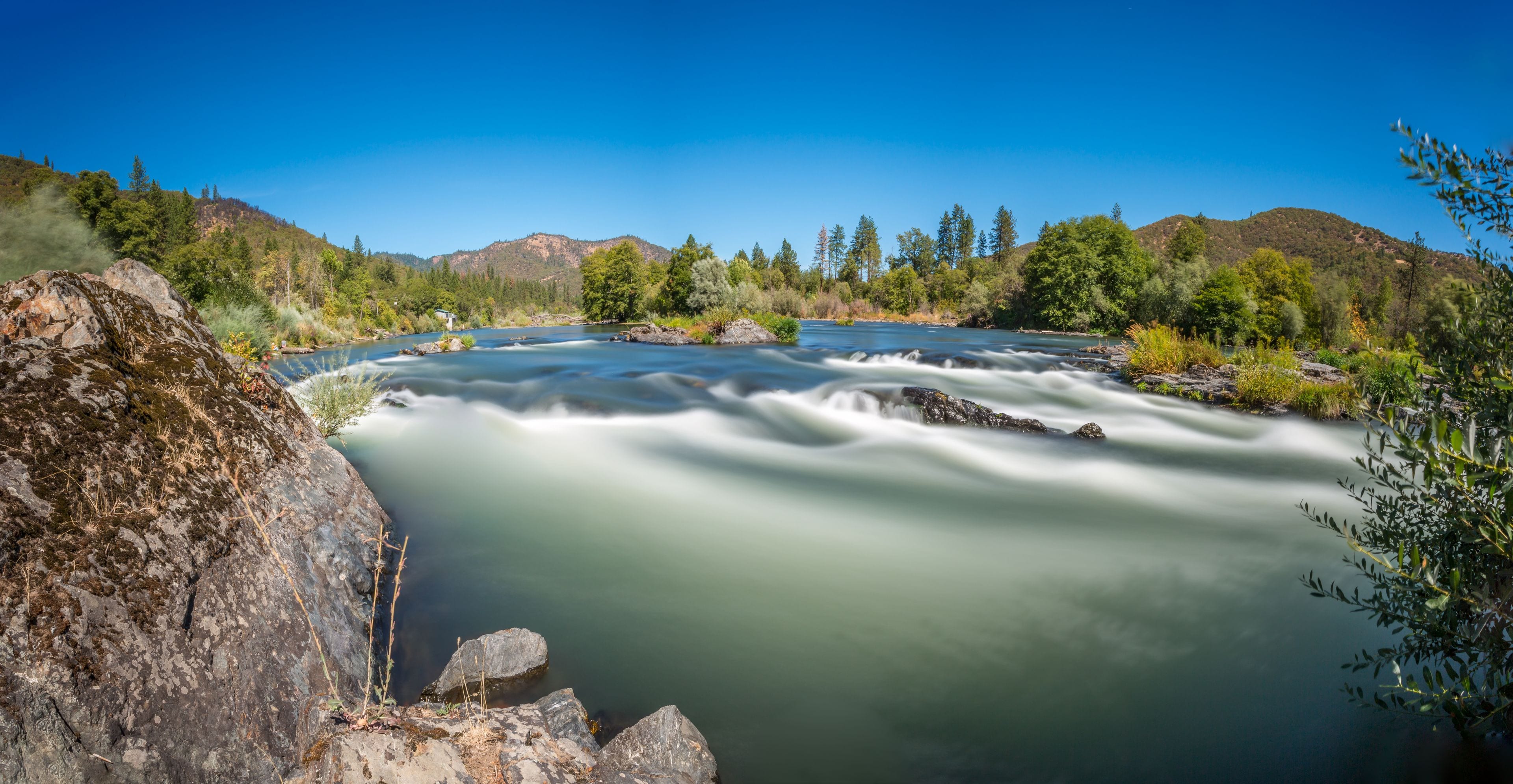 Un río que serpentea por un paisaje montañoso con cielos despejados.