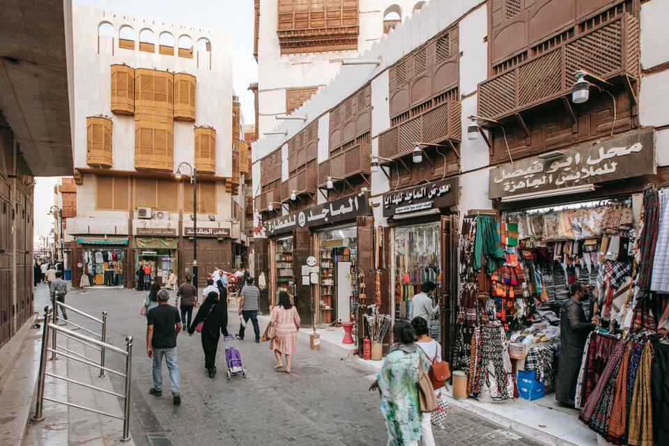 A bustling street with traditional architecture, shops selling textiles, and pedestrians.
