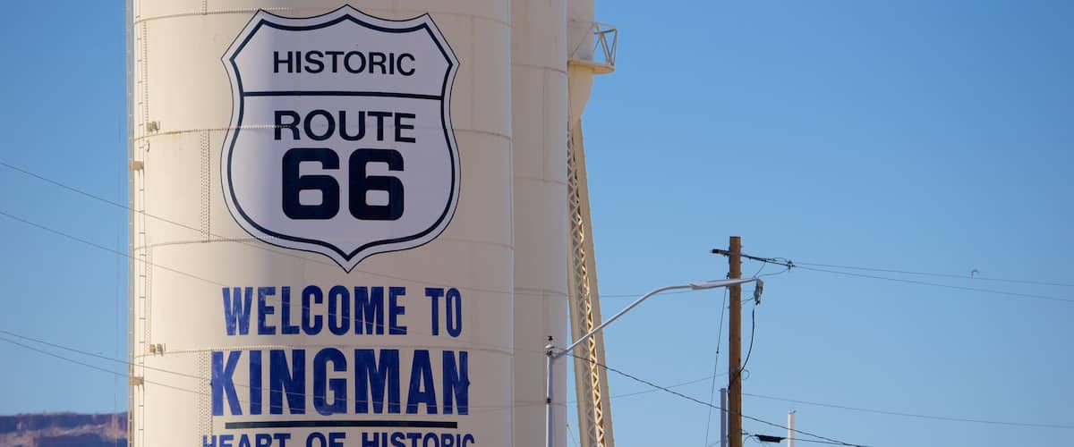 A large white sign with blue lettering that reads "Historic Route 66 Welcome to Kingman Heart of Historic Route 66."