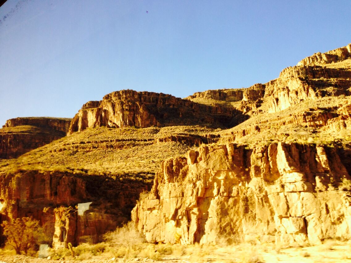 A canyon with layered rock formations and sparse vegetation.