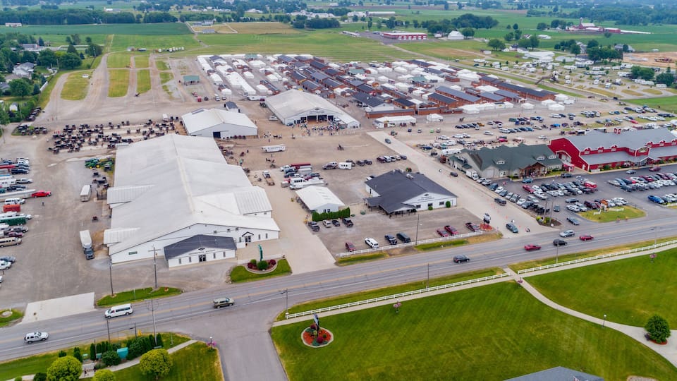 An industrial area with large warehouses, a parking lot, and a road with vehicles.