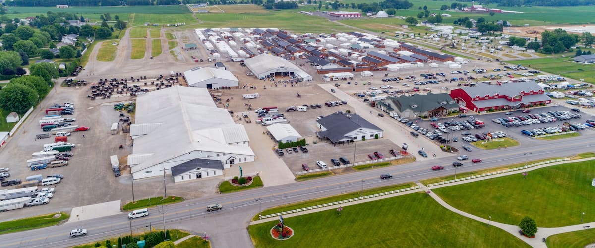 An industrial area with large warehouses, a parking lot, and a road with vehicles.