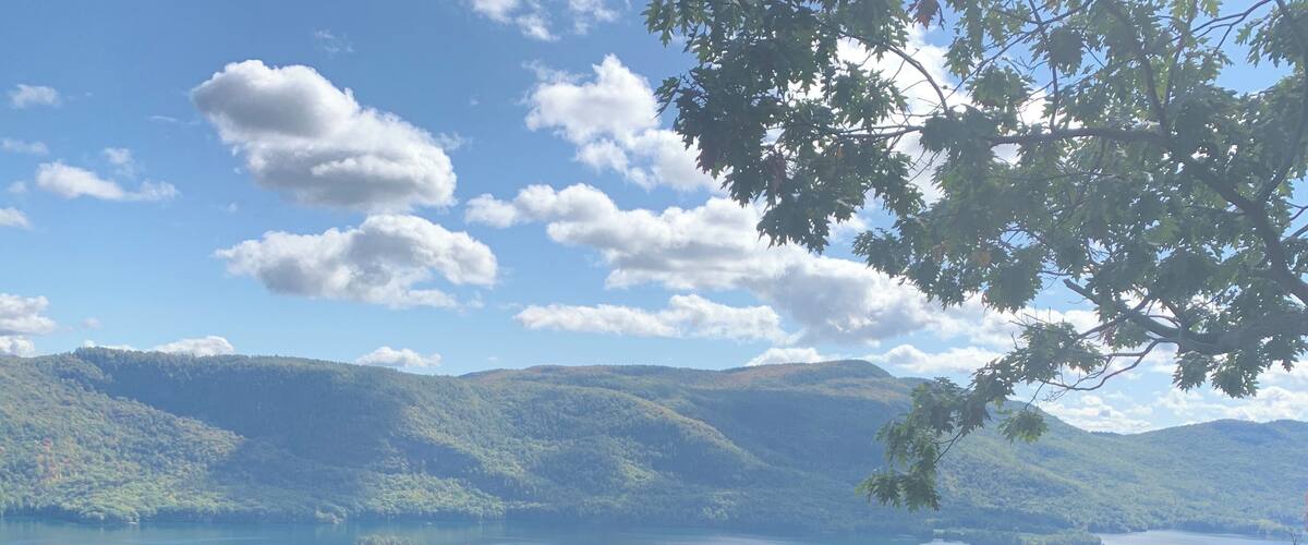 A lake surrounded by forested hills under a partly cloudy sky.