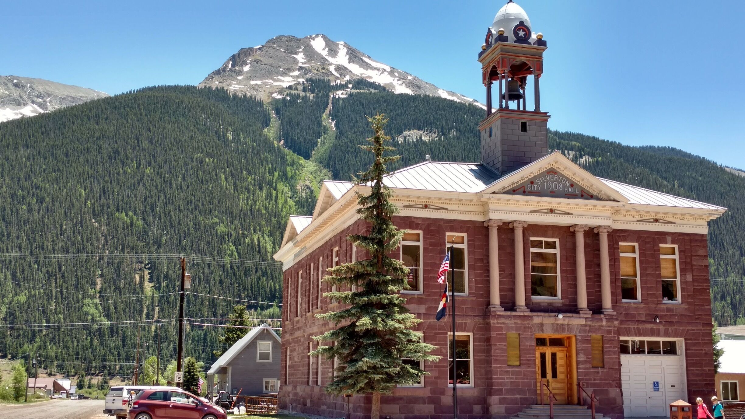 A historic building with a bell tower, surrounded by a mountainous landscape.