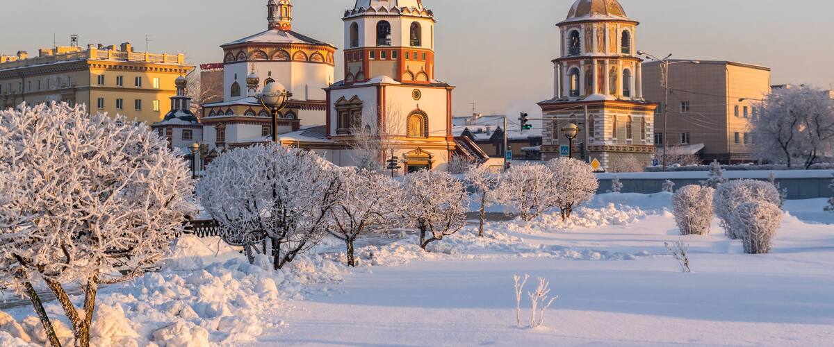 A snow-covered landscape with historic buildings and a prominent church with multiple domes.
