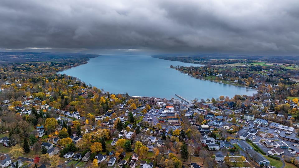 A lake surrounded by autumn-colored trees and a residential area.