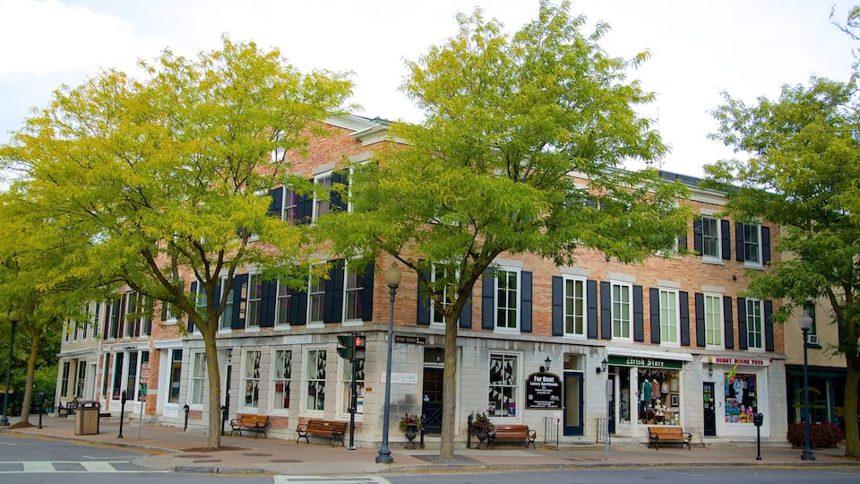 A street with a row of brick buildings, benches, and trees.