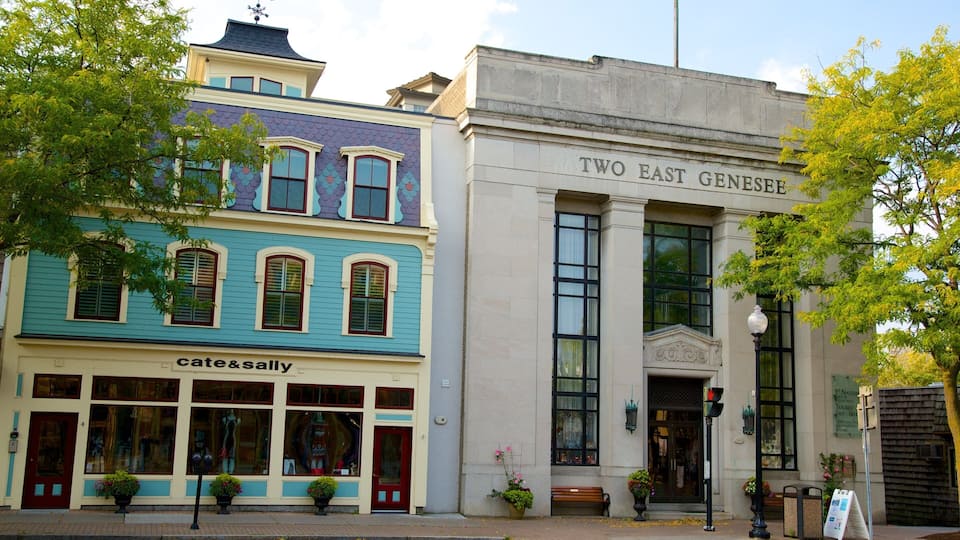 A colorful building with a 'Cates & Sally' sign, a 'Two East Genesis' sign, and a street with trees and a bench.