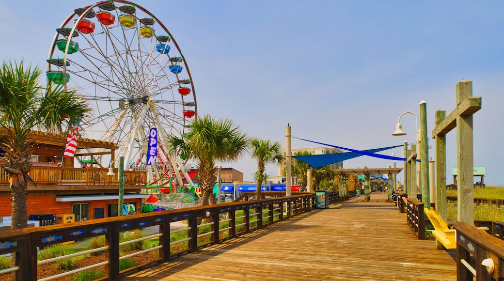 A sunny view down a wooden boardwalk and a large Ferris wheel at the Carolina Beach Amusement Park in Wilmington, North Carolina in the USA.