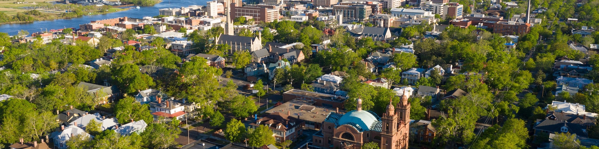 An aerial view of a city with a river, a bridge, and a prominent church with a blue dome.