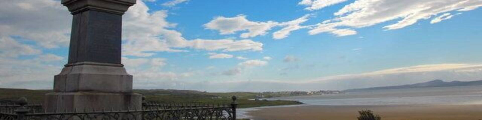 Monument, near Bridgend, Islay. The inscription reads:- John Francis Campbell, of Islay, an eminent Celtic scholar linguist scientist & traveller, a true and patriotic highlander, loved alike by peer and peasant, by his, popular tales of the west Highlands, "Leabhar na Feinne", and other literary works, he preserved and rendered classic the, folk-lore of the Scottish Highlands. He lies buried at Cannes in France, his memory lives in the hearts of his countrymen. Born 1821 Died 1885