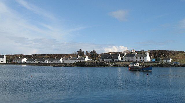 A coastal village with white houses and a boat on the water.