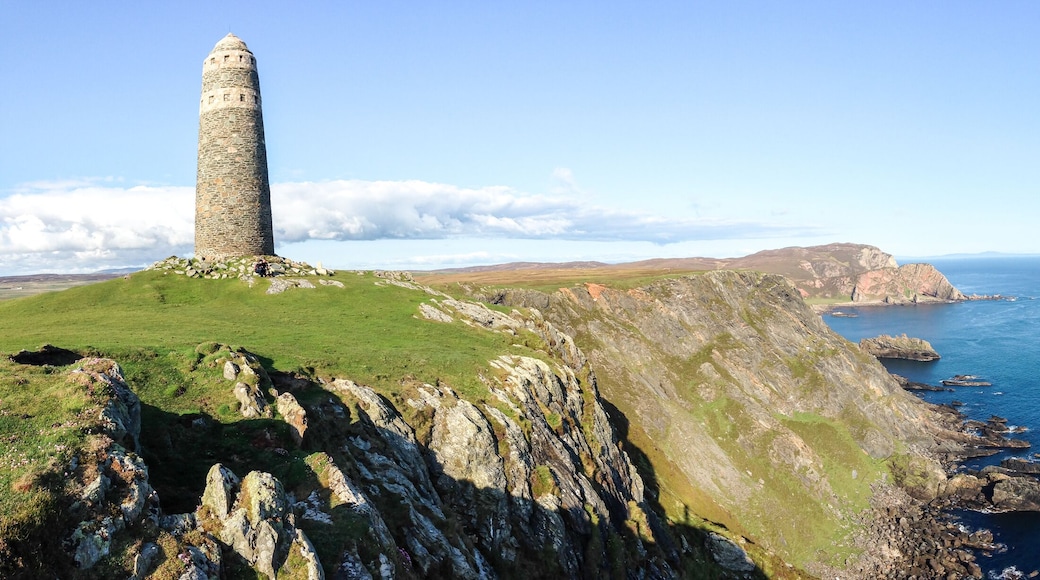 A large rock tower sits on a grassy field at the tip of the Oa Peninsula on the island of Islay in Scotland.
