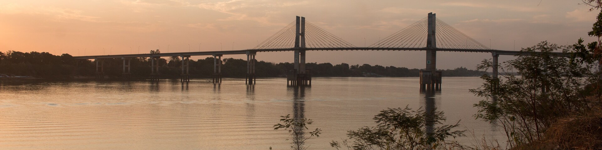 Un puente colgante sobre un río tranquilo al atardecer.