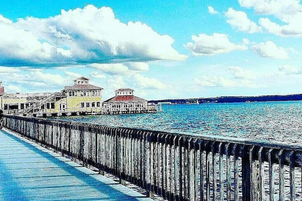 Eine Uferpromenade mit Holzsteg und Gebäuden mit roten Dächern.