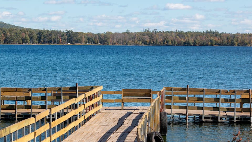 A wooden pier extending into a calm lake, surrounded by a forested shoreline.