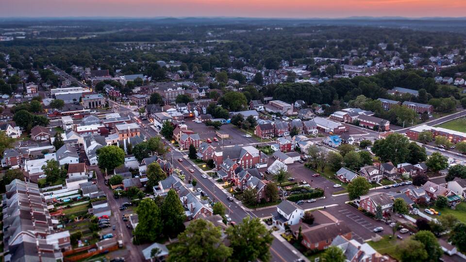 An aerial view of a suburban town with a mix of residential houses, a church, and a large parking lot.