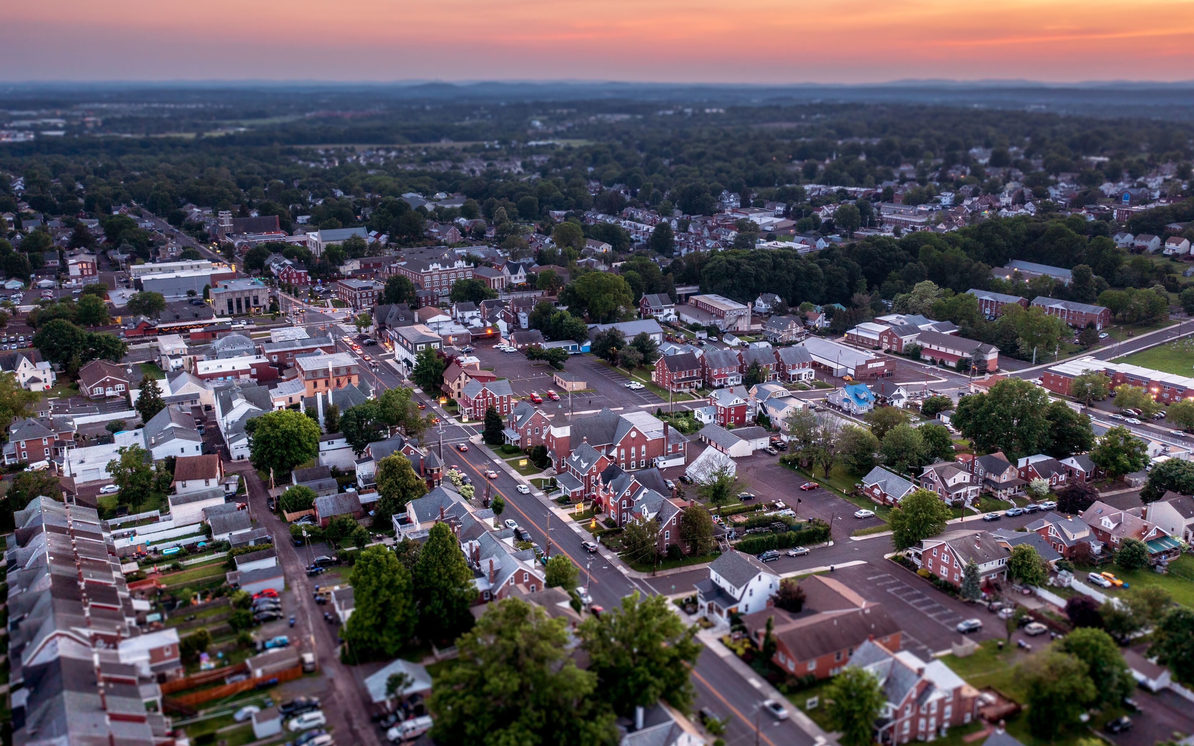 An aerial view of a suburban town with a mix of residential houses, a church, and a large parking lot.