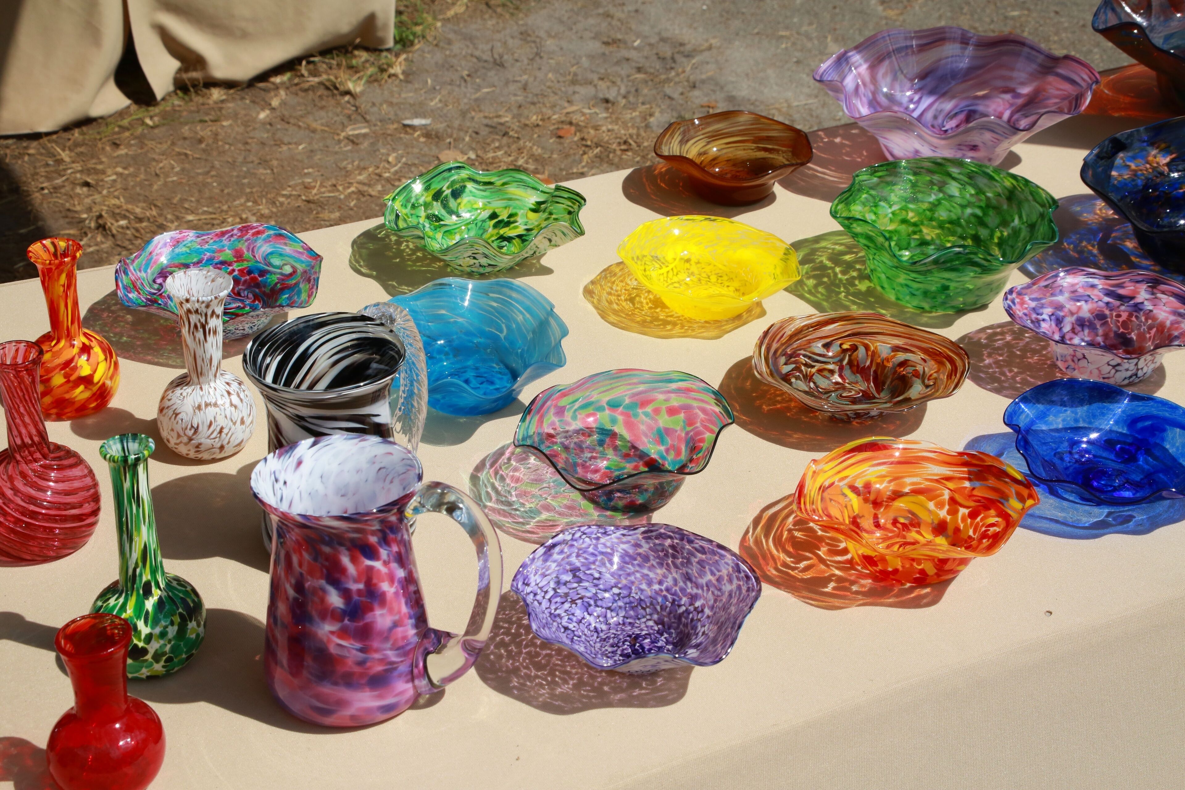 A collection of colorful glass vases and bowls on a table.