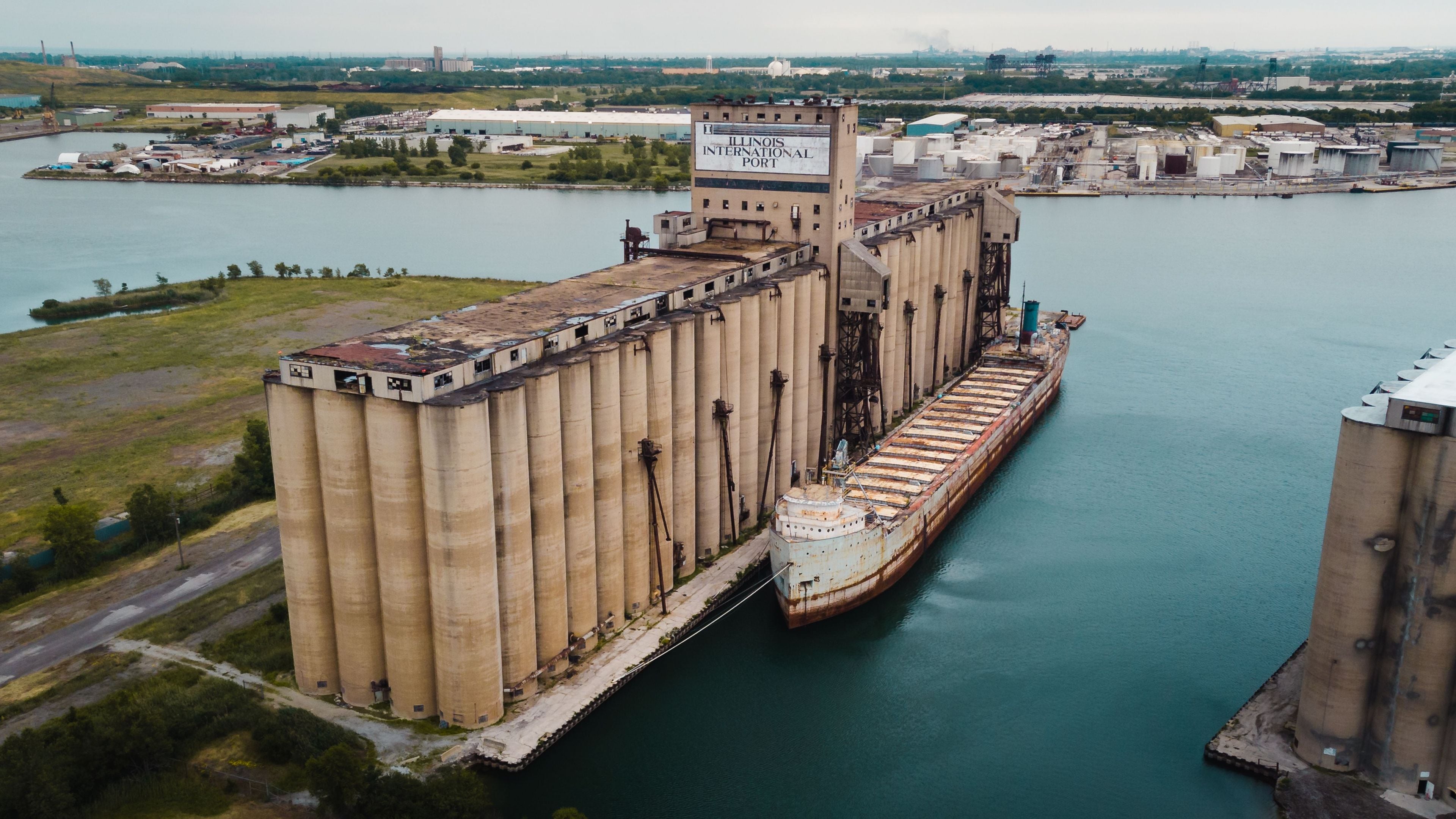 Et stort industrikompleks med et markant kornsilo og et skib ved en havn.
