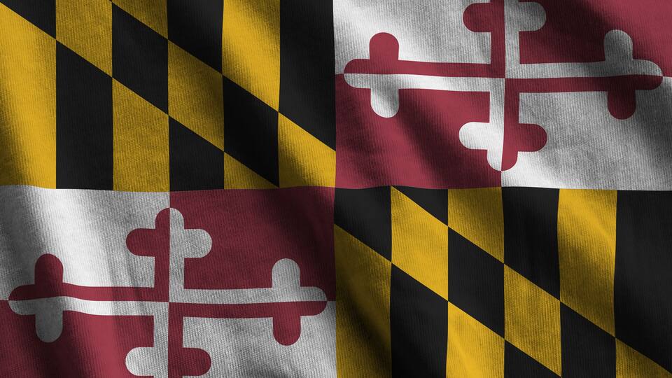 Maryland US state flag with big folds waving close up under the studio light indoors. The official symbols and colors in fabric banner