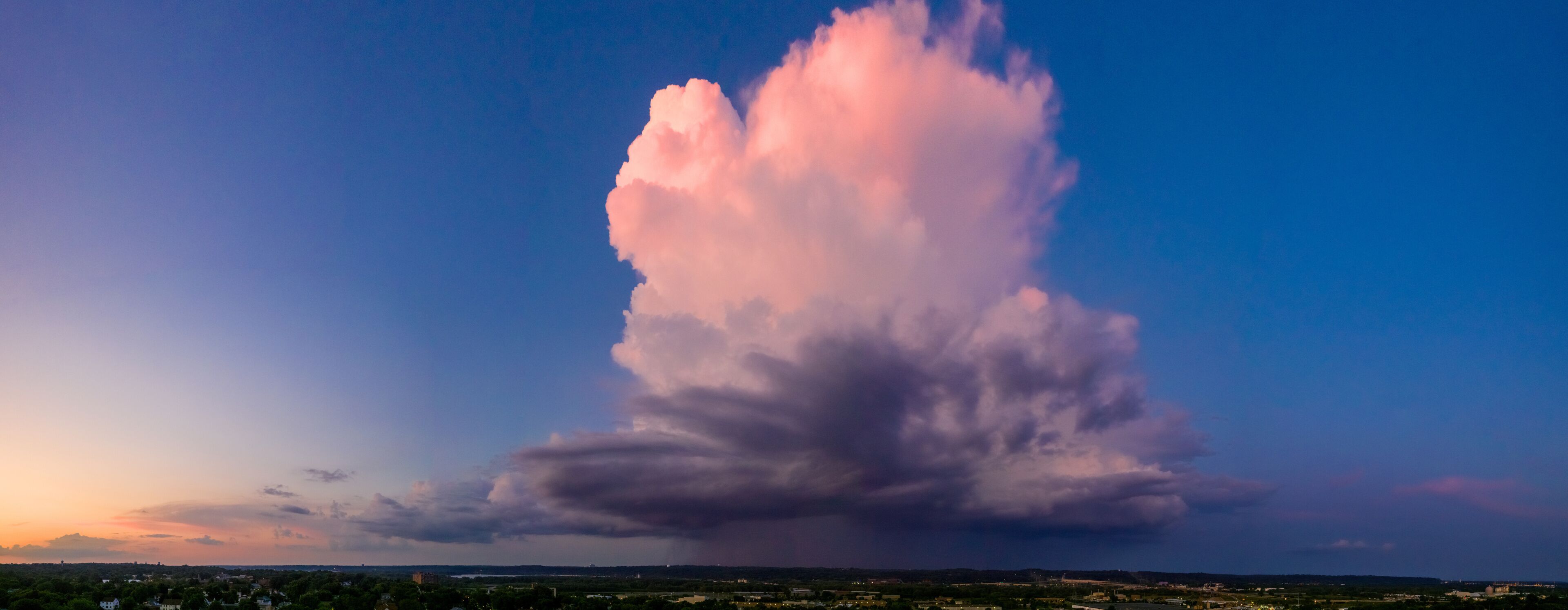 A large cloud formation over a cityscape at sunset.