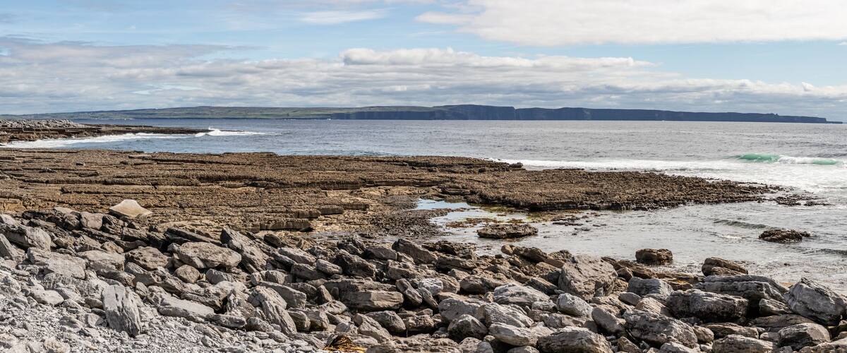 A rocky coastline with a lighthouse in the distance.