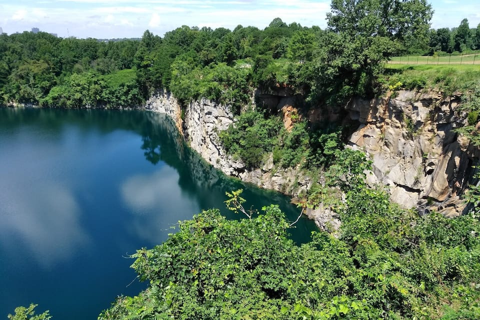 A serene lake surrounded by lush greenery and rocky cliffs.