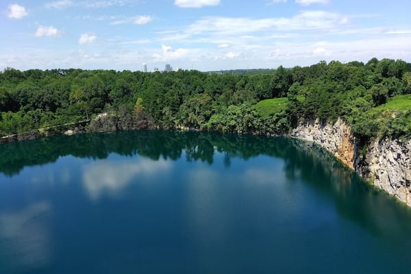 En rolig sø omgivet af tæt skov og klippefremspring.