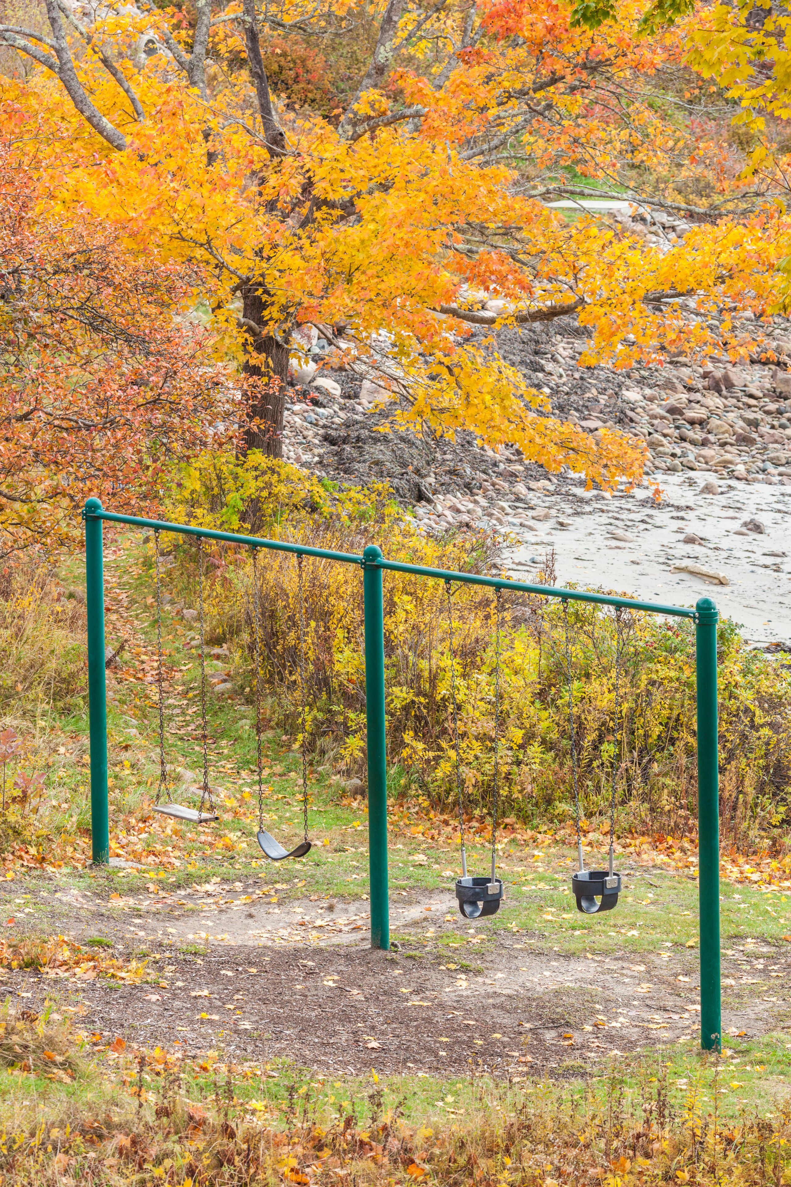 USA, Maine, Mt. Desert Island. Seal Harbor, seaside children's swing set during autumn.