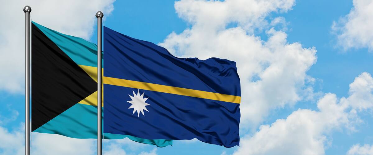 Two flags waving against a blue sky with clouds.