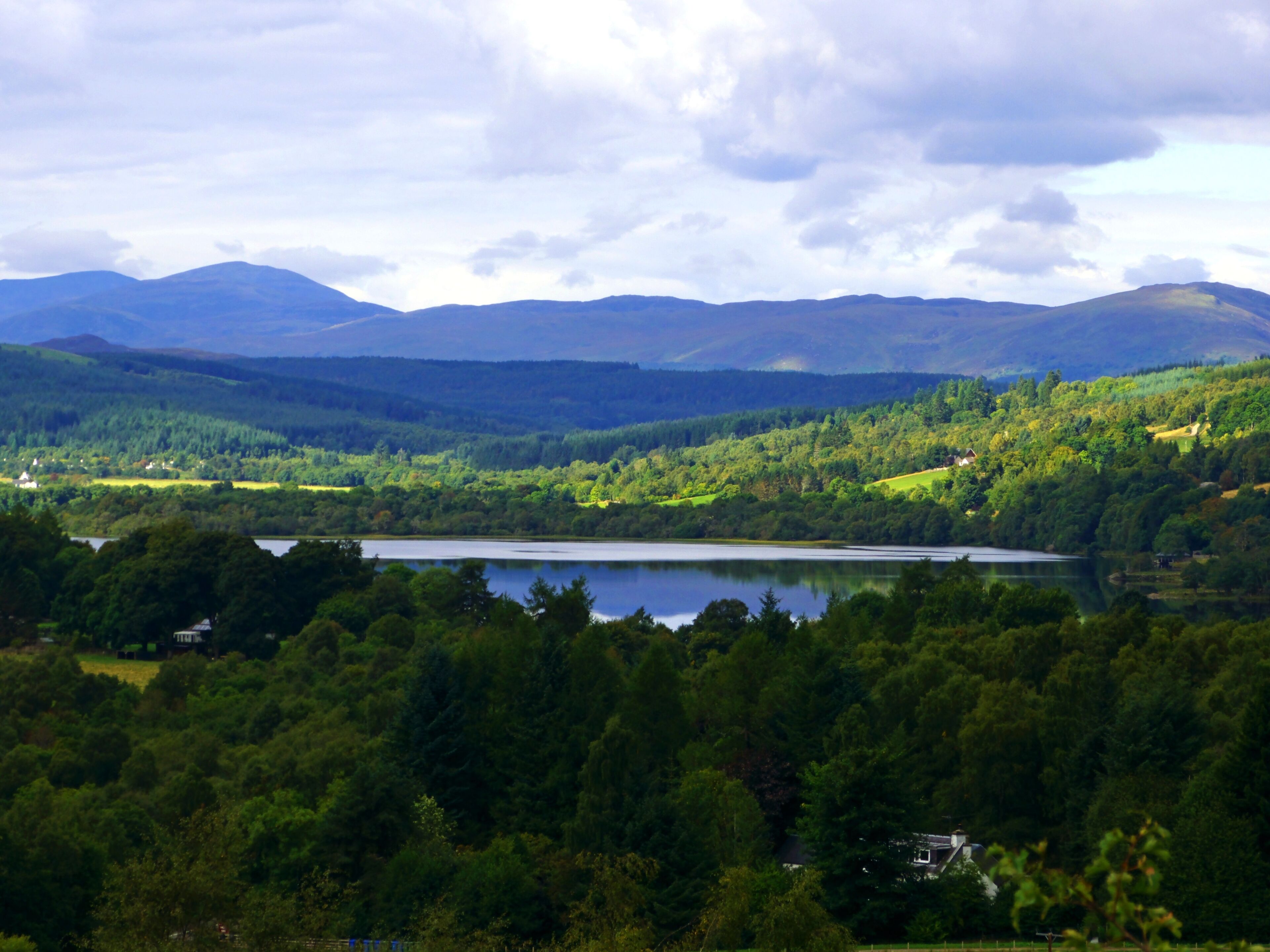 A lake surrounded by forested hills and mountains.