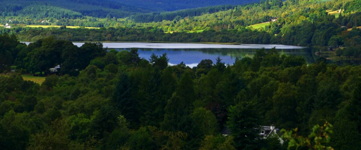 A lake surrounded by forested hills and mountains.