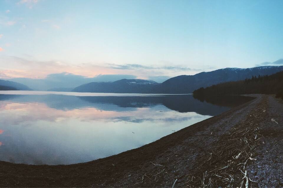 Un lago tranquillo circondato da montagne e un cielo sereno.