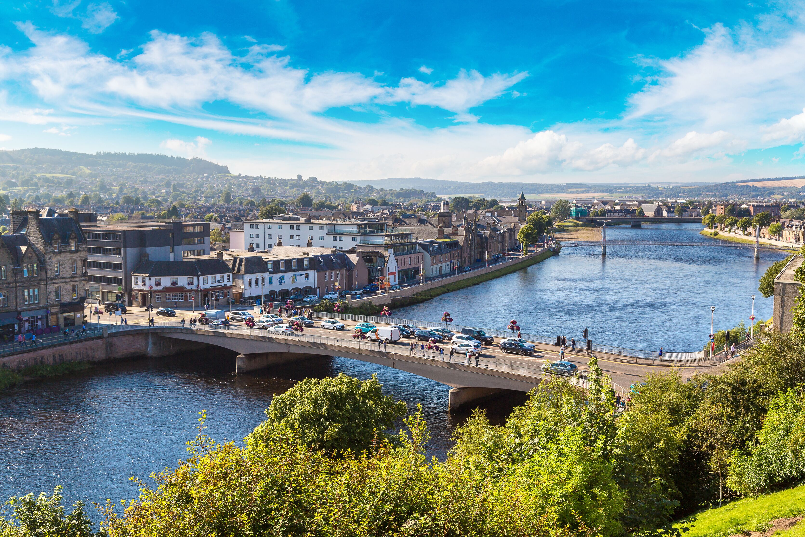 A river with a bridge, buildings, and a distant hill.