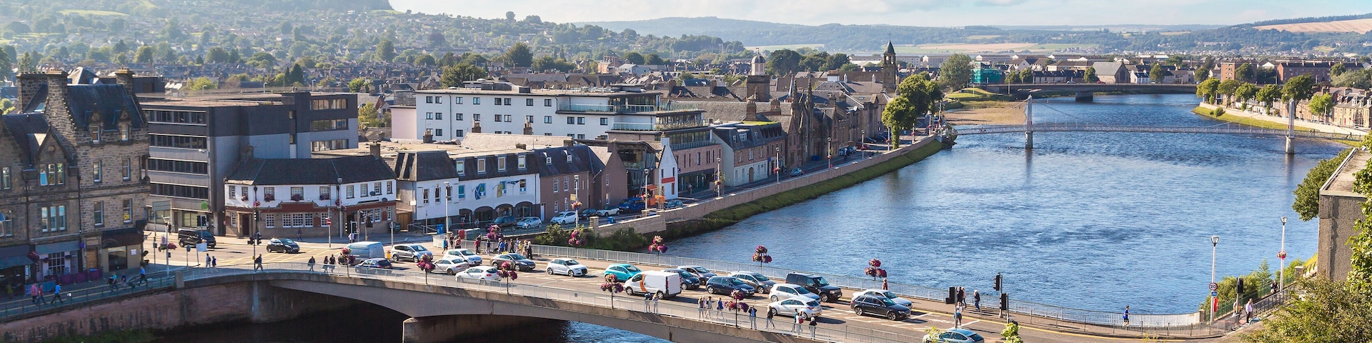 A river with a bridge, buildings, and a distant hill.