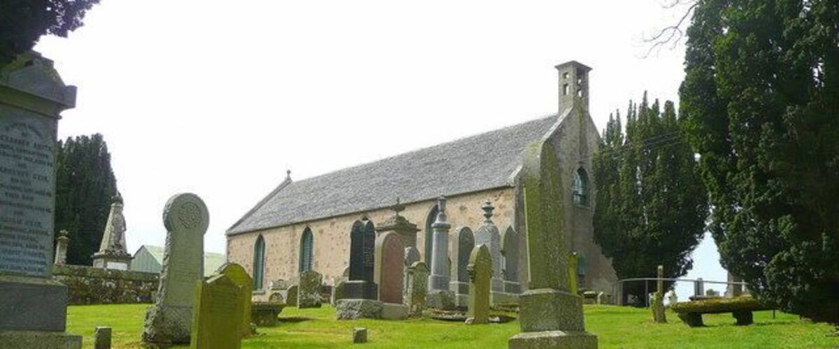A church with a stone facade and a graveyard with headstones.