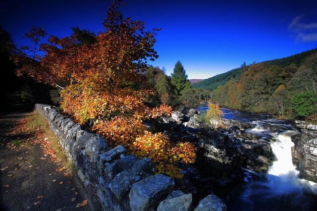 A river flowing through a rocky gorge with autumn foliage.