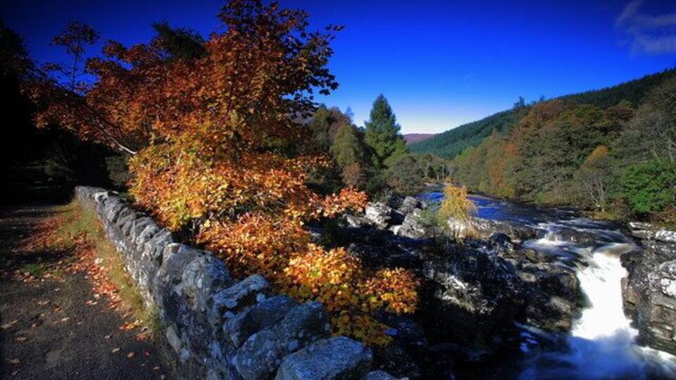 A river flowing through a rocky gorge with autumn foliage.