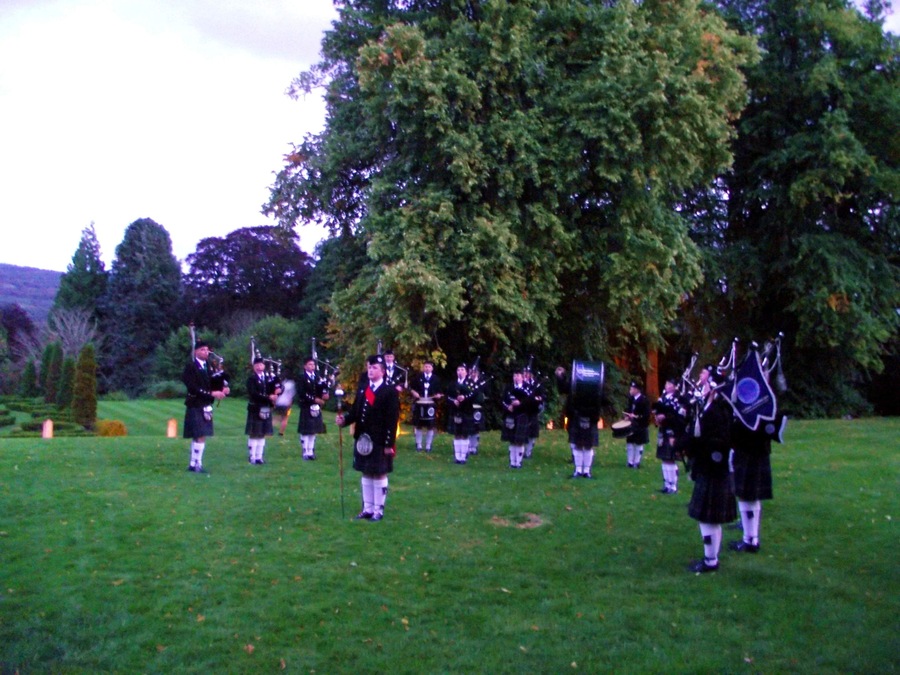 Band forms a semi circle on the lawn in front of the Castle in twilight. BAND AT ACHNAGAIRN CASTLE - The band were delighted to be asked to perform at the International Social Travel Summit Gala Dinner tonight at the beautiful Achnagairn Castle near inverness. The summit was attended by over 120 delegates from a considerable number of countries, and we were more than happy to entertain them outside this historic and beautiful building. Our slot was between the delegates arrival and their going into dinner. Pipe Major Steve Spencer was playing out on the front lawn in the gloaming - and the guests lapped up the "solo piper" performance - only for them to whoop with delight when the surprise appeared, the full Band marching out from the side of the Castle to join the Pipie on the lawn. Despite work and health issues at short notice, which saw the number of pipers diminished somewhat, we were still able to field ELEVEN pipers, SEVEN snare drummer, a bass and a Drum Major (20 in total). The delegates were obviously enjoying the performance when, all too soon, it was time for the Band to conclude and march off, so the guests could go to dine. Despite the failing light, hopefully my photographs will give a hint of the occasion - being an international event, VisitScotland anticipate many far better photos than mine all over the internet before long!