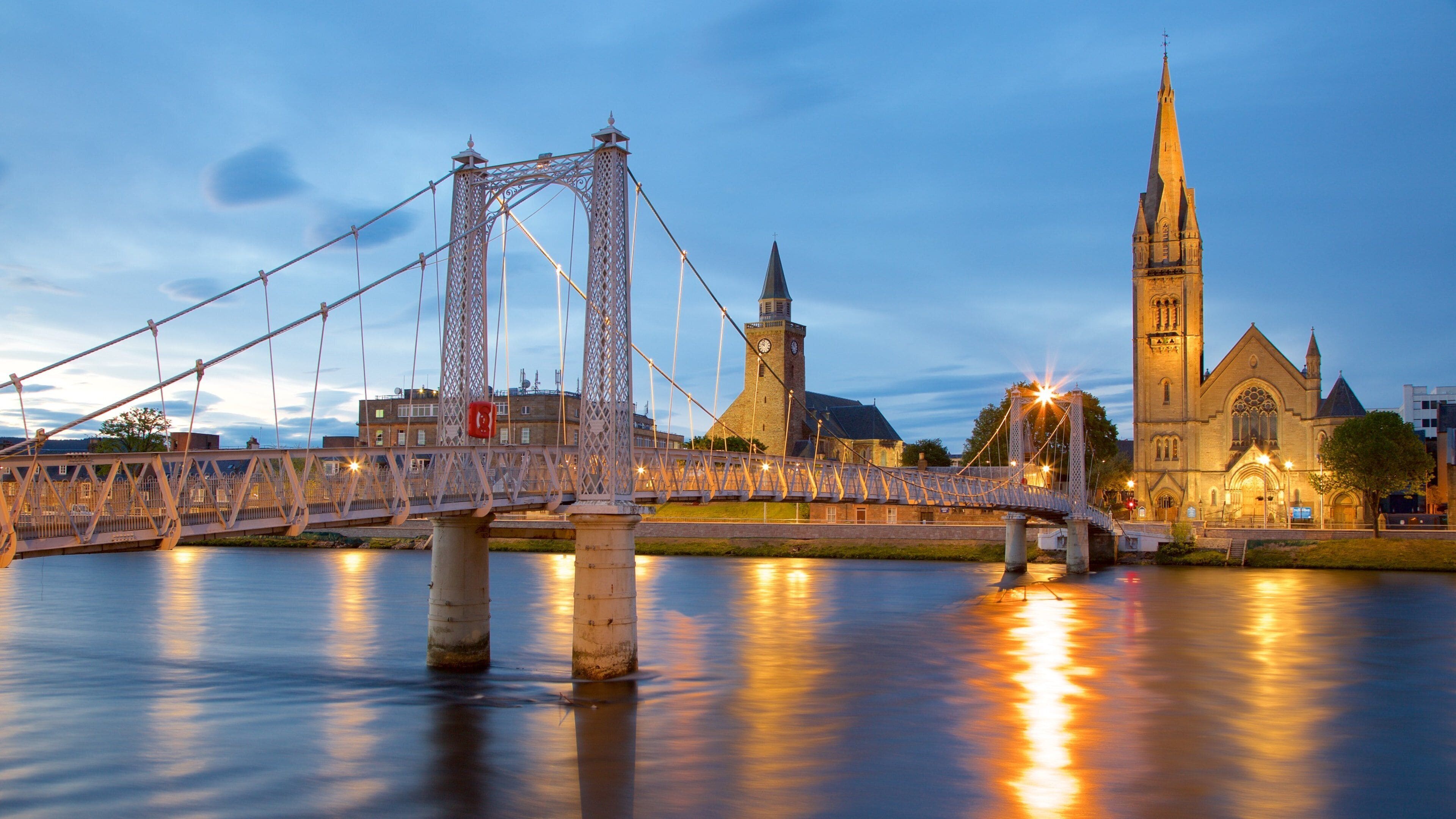 A bridge over a river with a church and a tower in the background.