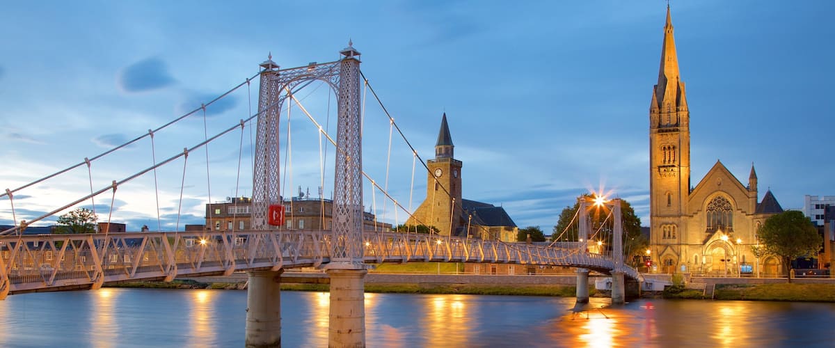 A bridge over a river with a church and a tower in the background.