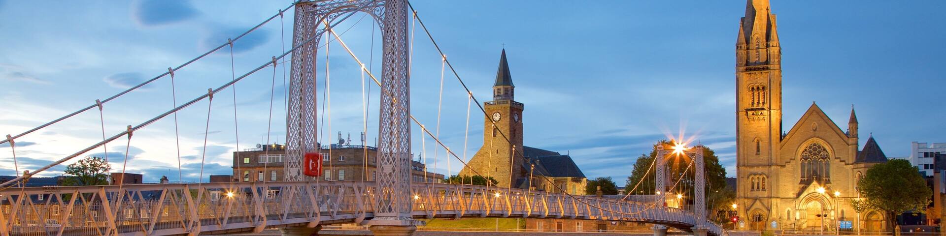 A bridge over a river with a church and a tower in the background.