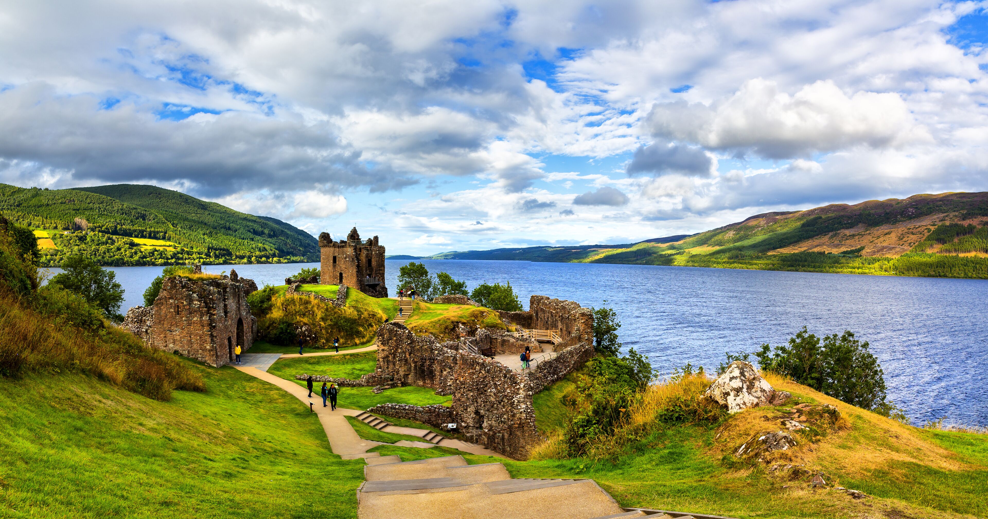A historic castle ruin by a lake with a clear sky.