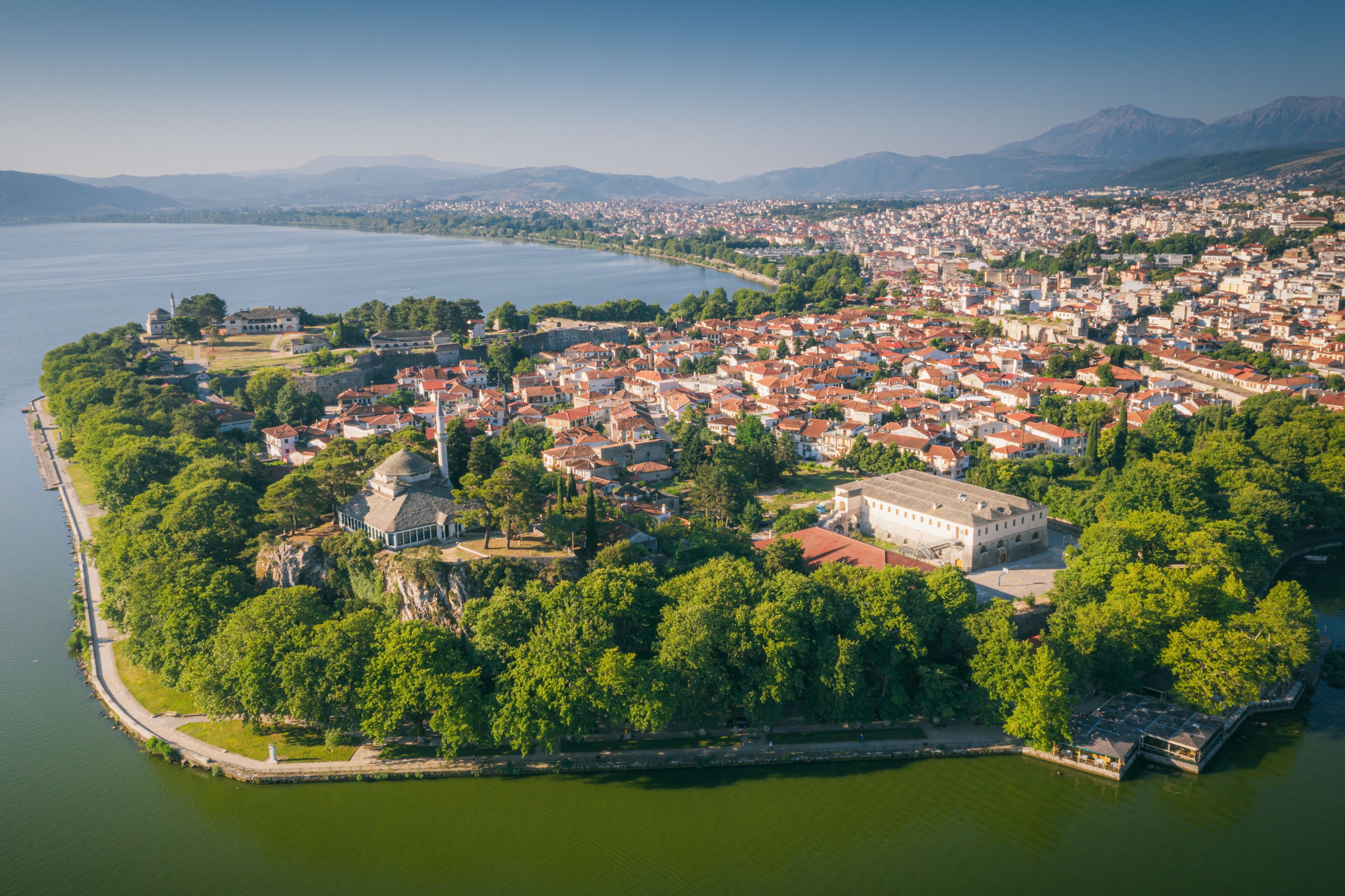 An aerial view of a coastal town with a prominent historical building, dense residential area, and a large body of water.